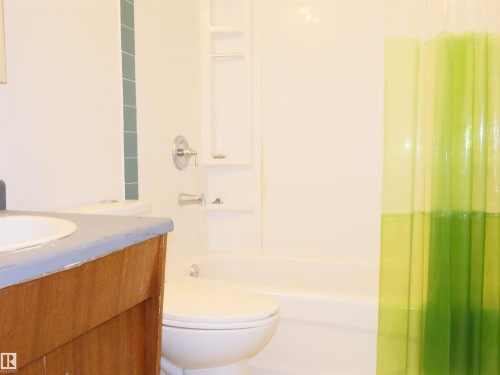 Full bathroom featuring a white tub, chrome fixtures, and a white toilet - 4934 49 Avenue, Barrhead, AB - Indoor Photo Showing Bathroom