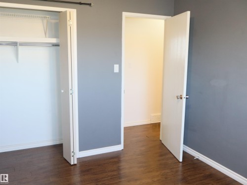 Interior featuring wood-finish flooring, two-panel interior doors, a bi-fold closet door, and a built-in closet shelf with a hanging rod - 4934 49 Avenue, Barrhead, AB - Indoor Photo Showing Other Room