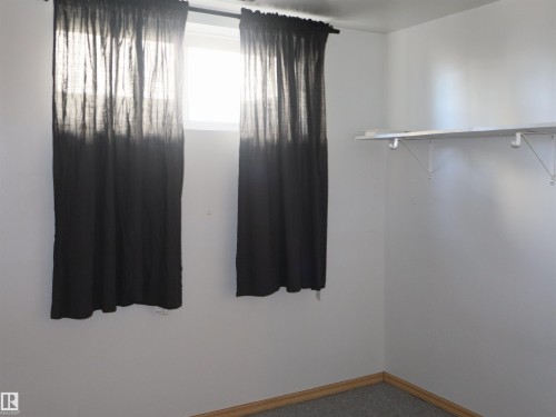 Carpeted room with a single window and built-in shelving - 4934 49 Avenue, Barrhead, AB - Indoor Photo Showing Other Room