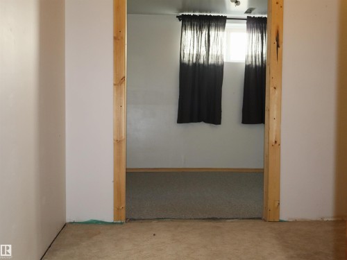 Room entry featuring an unfinished wood door frame, carpeted flooring, and a white-painted wall with a window - 4934 49 Avenue, Barrhead, AB - Indoor Photo Showing Other Room