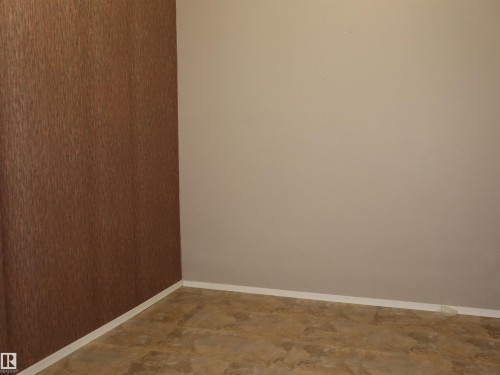 Interior space featuring a textured brown wall, a smooth beige wall, and patterned floor tiling - 4934 49 Avenue, Barrhead, AB - Indoor Photo Showing Other Room