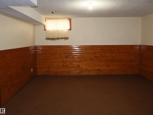 Carpeted room featuring wood-paneled walls and a window - 4934 49 Avenue, Barrhead, AB - Indoor Photo Showing Other Room