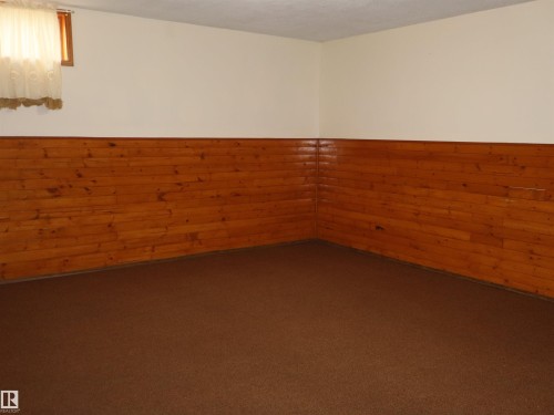 Finished room with warm wood paneling, light-colored walls, and a window - 4934 49 Avenue, Barrhead, AB - Indoor Photo Showing Other Room