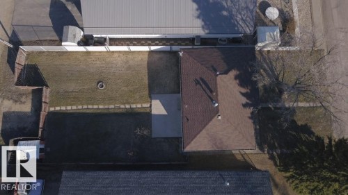 Aerial perspective showcasing a brown shingle roof, a concrete patio, and a grass lawn - 4934 49 Avenue, Barrhead, AB - Outdoor