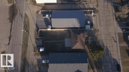 Property featuring a brown shingle roof, a rectangular backyard with a manicured lawn, and a large detached garage with a metal roof - 4934 49 Avenue, Barrhead, AB - Indoor