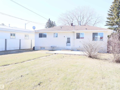 Rear exterior featuring a concrete patio, stucco siding, and a gabled roof - 4934 49 Avenue, Barrhead, AB - Outdoor