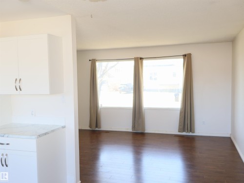 Open-concept living area featuring rich wood-finish flooring, white walls, and a large window with three panes - 4934 49 Avenue, Barrhead, AB - Indoor Photo Showing Other Room