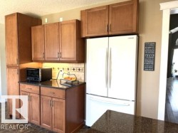 Kitchen cabinetry featuring warm wood-finish doors and dark countertops - 