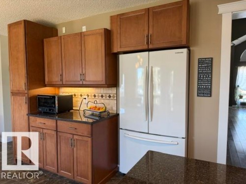 Kitchen featuring extensive wood cabinetry, dark countertops, a tiled backsplash, and recessed lighting - 356 Weber Way, Edmonton, AB - Indoor Photo Showing Kitchen
