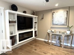 Built-in entertainment center featuring an integrated electric fireplace, open shelving, recessed lighting, and wood-finish flooring - 