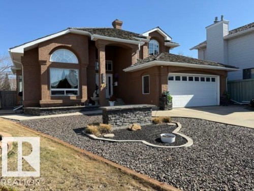 Stucco exterior with stone accents, featuring a prominent arched window and a two-car garage - 356 Weber Way, Edmonton, AB - Outdoor