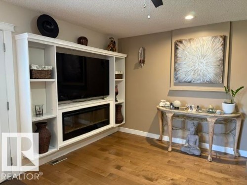 Built-in media center featuring white cabinetry, integrated shelving, and an electric fireplace - 356 Weber Way, Edmonton, AB - Indoor With Fireplace