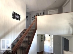 Staircase with carpeted treads, dark wood handrail, and black metal balusters - 