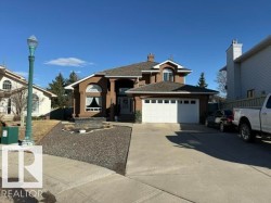 Stucco exterior featuring an arched window, a two-car garage, and a concrete driveway - 