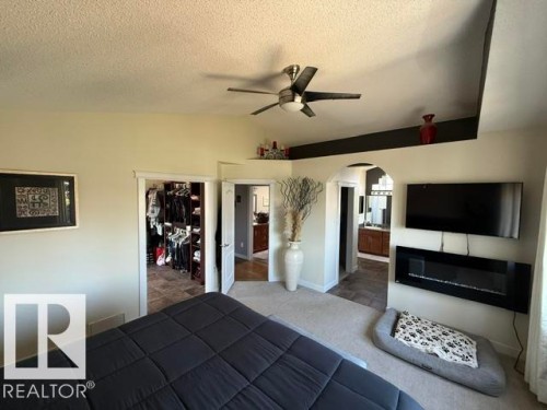 Bedroom featuring a ceiling fan, tray ceiling, and a wall-mounted electric fireplace - 356 Weber Way, Edmonton, AB - Indoor Photo Showing Other Room