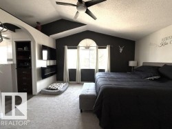 Vaulted ceilings with a ceiling fan, a prominent arched window, and built-in dark wood cabinetry - 