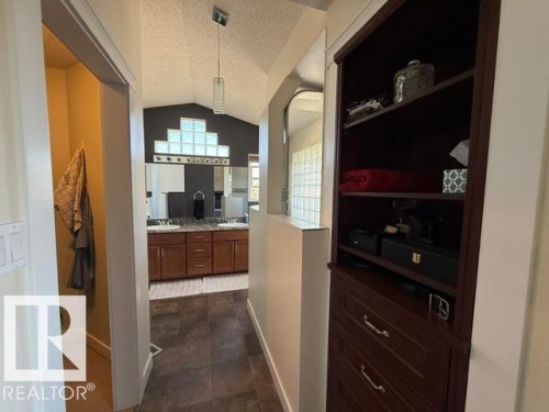 Bathroom featuring vaulted ceilings, a dual vanity with a granite countertop, dark wood cabinetry, and glass block window accents - 356 Weber Way, Edmonton, AB - Indoor Photo Showing Other Room