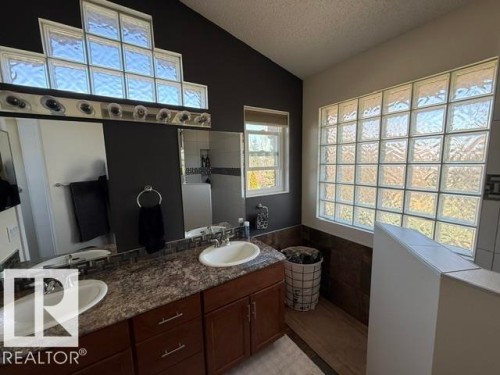 Bathroom featuring a dual vanity with undermount sinks, a speckled countertop, and dark wood-finish cabinetry - 356 Weber Way, Edmonton, AB - Indoor Photo Showing Bathroom