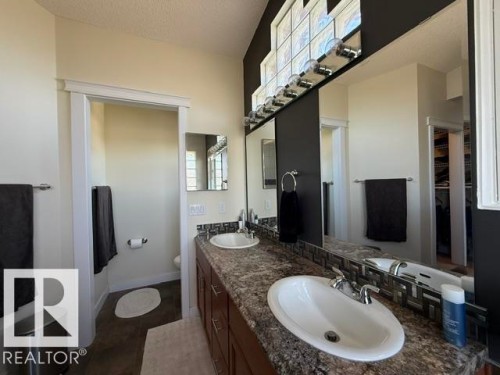 Dual sink vanity featuring a granite-style countertop, integrated sinks, and chrome fixtures - 356 Weber Way, Edmonton, AB - Indoor Photo Showing Bathroom