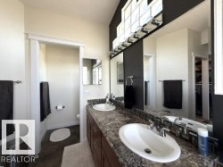 Dual oval undermount sinks set in a granite-look countertop with dark wood-finish cabinetry - 
