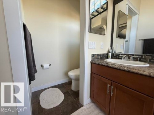 Bathroom vanity featuring a dark wood-finish cabinet with silver-tone hardware, an undermount sink, and a speckled countertop - 356 Weber Way, Edmonton, AB - Indoor Photo Showing Bathroom