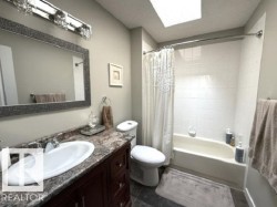 Bathroom featuring a dark wood vanity with an oval undermount sink, a patterned countertop, and a decorative framed mirror - 