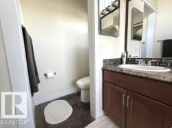 Bathroom featuring a dark wood-finish vanity with an undermount sink, a patterned tile backsplash, and dark tile flooring - 