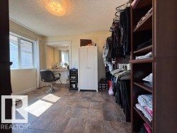 Spacious room featuring tile flooring, a large window, a built-in vanity with mirror, and extensive custom built-in shelving - 