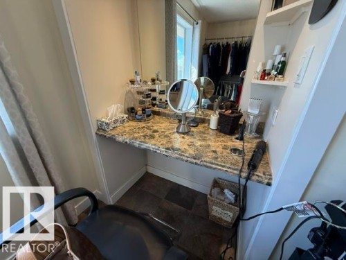 Built-in vanity with a stone-finish countertop, integrated mirror, recessed lighting, and open shelving - 356 Weber Way, Edmonton, AB - Indoor