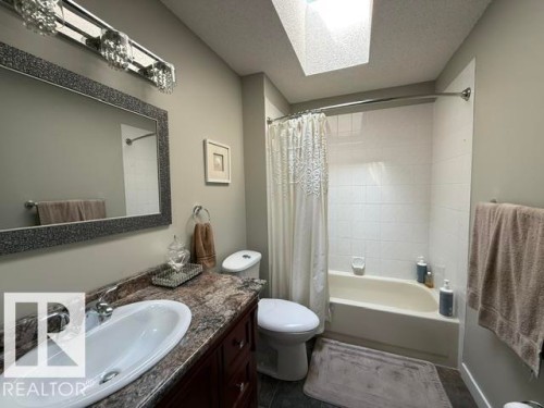 Full bathroom featuring a vanity with an oval undermount sink, a marbled countertop, and a dark wood-finish cabinet - 356 Weber Way, Edmonton, AB - Indoor Photo Showing Bathroom