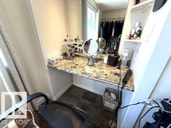 Built-in vanity with a stone-finish countertop, integrated mirror, and built-in shelving - 