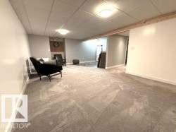 Expansive carpeted area featuring a neutral gray palette, recessed lighting, and a visible wood beam detail - 
