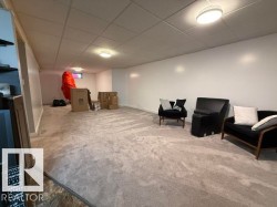 Spacious room featuring light gray carpet, white painted walls, and a drop ceiling with recessed lighting - 
