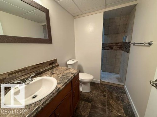 Bathroom featuring a dark wood-finish vanity with an oval sink, a stone-look countertop, and a tiled backsplash - 356 Weber Way, Edmonton, AB - Indoor Photo Showing Bathroom