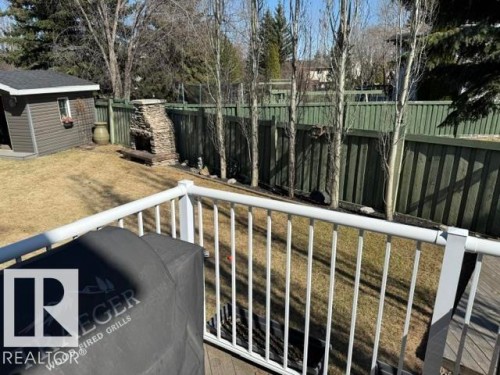 Expansive backyard featuring a stone outdoor fireplace, a storage shed with siding, and a privacy fence - 356 Weber Way, Edmonton, AB - Outdoor With Exterior