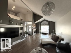 Vaulted ceilings with an intricate chandelier, wood-finish flooring, and a built-in media center - 