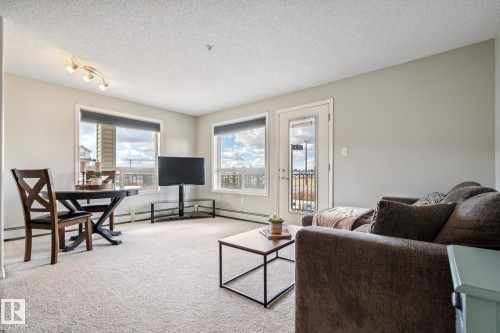 Living space featuring light-toned carpeting, neutral wall paint, and overhead track lighting - 1306 330 Clareview Station Drive, Edmonton, AB - Indoor Photo Showing Living Room