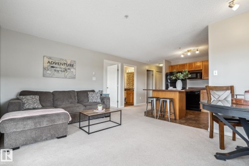 Open-concept living space featuring light-colored carpet flooring, recessed lighting, and a kitchen with wood cabinetry - 1306 330 Clareview Station Drive, Edmonton, AB - Indoor Photo Showing Living Room