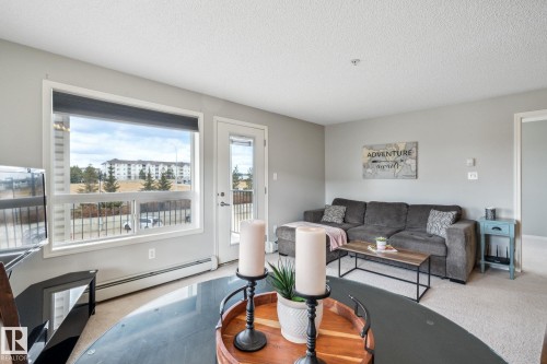 Living area featuring a large picture window, a glass-paneled exterior door, light-toned carpeting, and neutral wall paint - 1306 330 Clareview Station Drive, Edmonton, AB - Indoor Photo Showing Living Room