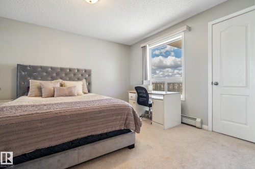 Carpeted room with a large window, a built-in desk, and a textured headboard - 1306 330 Clareview Station Drive, Edmonton, AB - Indoor Photo Showing Bedroom