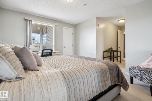 Carpeted room featuring a window with exterior vinyl siding visible, light neutral wall paint, and a white interior door - 1306 330 Clareview Station Drive, Edmonton, AB - Indoor Photo Showing Bedroom