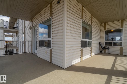 Expansive outdoor patio with concrete flooring, accented by horizontal siding and multiple windows - 1306 330 Clareview Station Drive, Edmonton, AB - Outdoor With Exterior