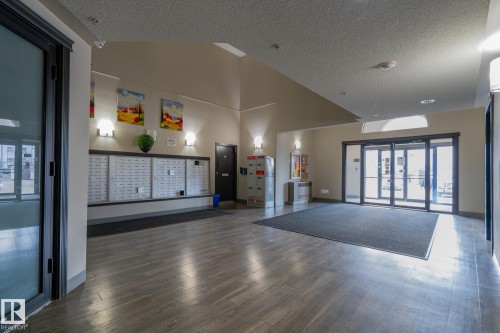 Building entryway featuring mailboxes, package lockers, wood-finish flooring, recessed lighting, and wall sconces - 1306 330 Clareview Station Drive, Edmonton, AB - Indoor Photo Showing Other Room
