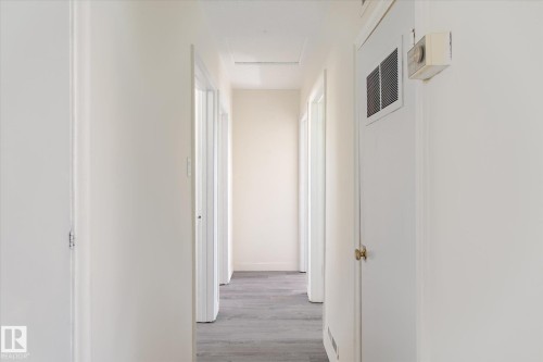Hallway with light gray wood-finish flooring, white walls, and multiple doorways - 10531 128 Avenue, Edmonton, AB - Indoor Photo Showing Other Room