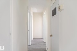 Hallway with light gray wood-finish flooring, white walls, and multiple doorways - 