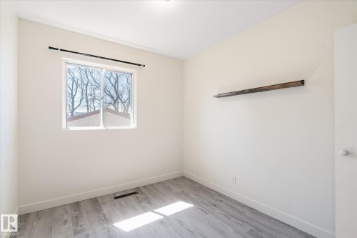 Room featuring light-toned walls, a single window with a black curtain rod, and wood-finish flooring - 10531 128 Avenue, Edmonton, AB - Indoor Photo Showing Other Room