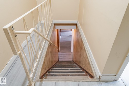 Staircase with wood-finish flooring, light-toned wall paneling, and a white metal railing - 10531 128 Avenue, Edmonton, AB - Indoor Photo Showing Other Room