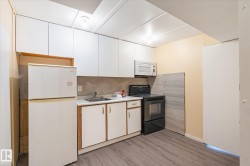 Kitchen featuring white upper cabinetry, a stainless steel sink, wood-finish flooring, a built-in microwave, and an electric range - 