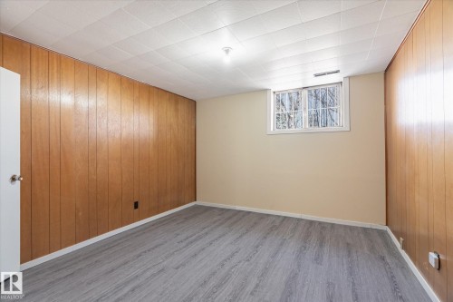 Room featuring a window with natural light, wood-finish paneling, light-toned painted walls, grey wood-finish flooring, and a white paneled ceiling - 10531 128 Avenue, Edmonton, AB - Indoor Photo Showing Other Room