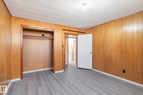 Room featuring wood paneling, wood-finish flooring, a white ceiling with recessed lighting, an open doorway, and a closet with a built-in shelf and hanging rod - 10531 128 Avenue, Edmonton, AB - Indoor Photo Showing Other Room